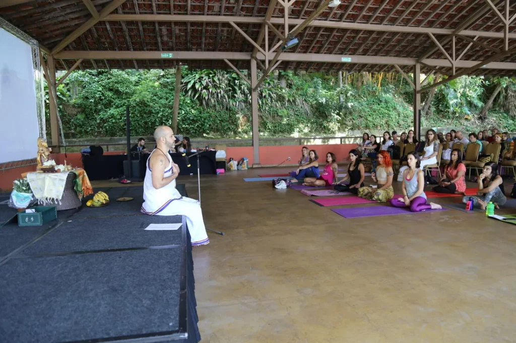 Palestra sobre Vedanta, com altar tradicional no palco e o público sentado em prática